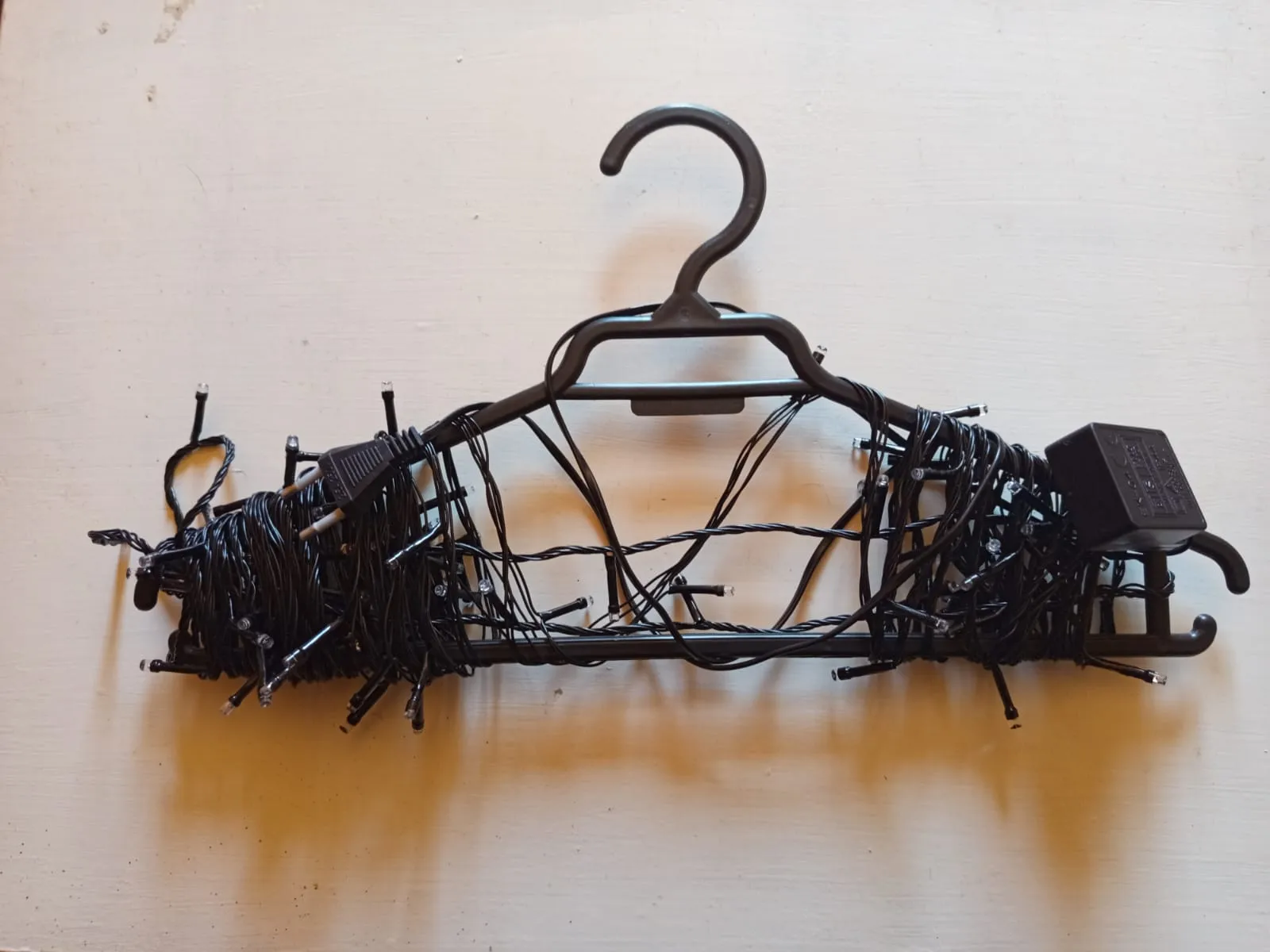 como-guardar-luces-navideñas-07 luces navideñas guardadas en un colgador de ropa